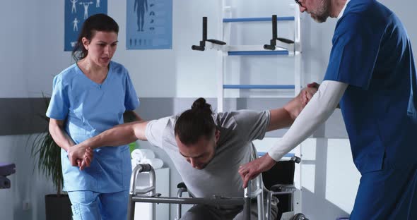 Handicapped Man Trying to Stroll with Walking Frame Near Doctors