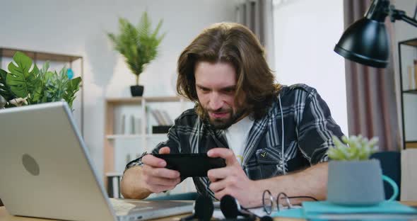 Man which Enjoying Games on Mobile at Home and Celebrating Victory