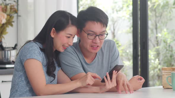 Young Asian couple enjoy shopping online on mobile phone at home.