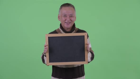 Happy Mature Japanese Man Talking While Holding Blackboard