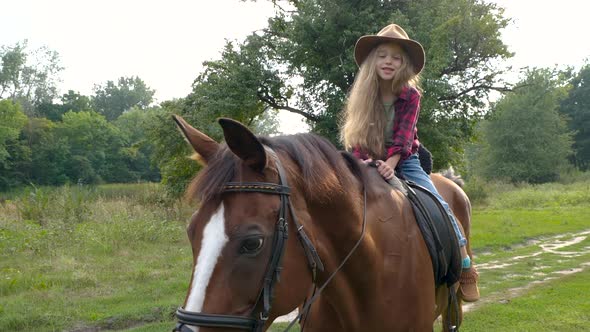 Young Cowgirl in Hat Riding Her Horse