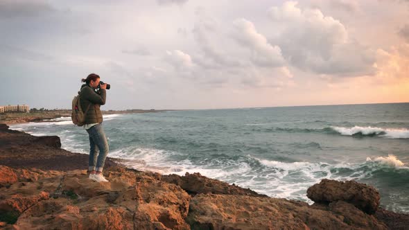 A Photographer Taking Pictures of Big Waves Crashing Against Rocks