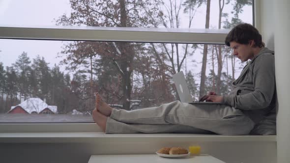 Man Sitting on the Window Sill Use Laptop