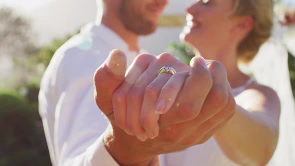 Portrait of happy caucasian newly wed couple, dancing in front of altar outdoors