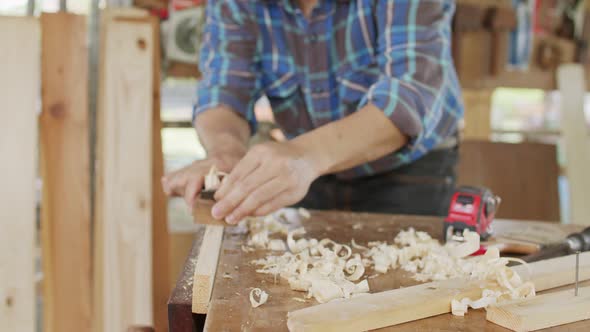 Close up carpenter planning to smooth the face of wood