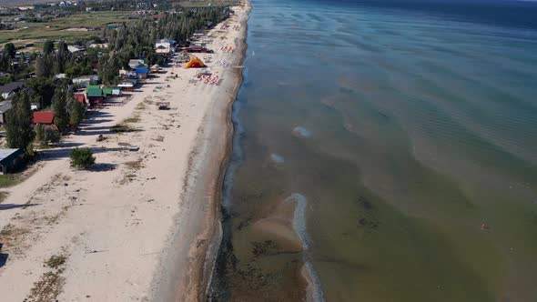 Beautiful flight in summer over the beach. People are resting near the sea. Houses for tourists.