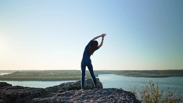 Silhouette of Yogi Woman Beginning Yoga Practice on Top of Rock on High Mountain