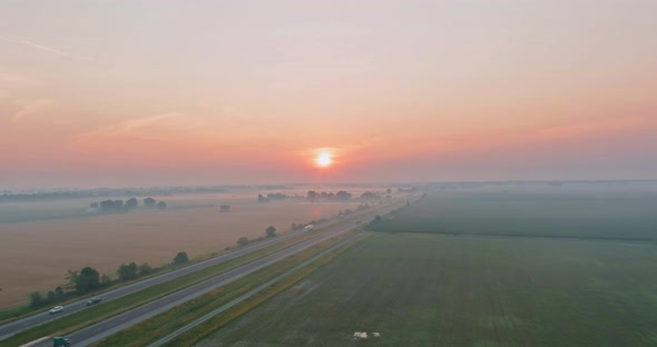 The Golden Hour Misty Morning with Orange Sun Rising Behind the Meadow Covered with Dense Fog