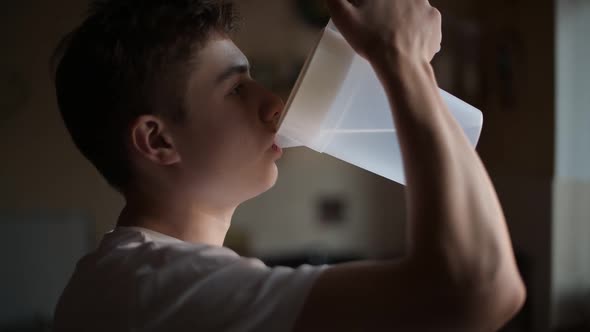 close-up of a sleepy teenager who drinks water in the morning and spills it