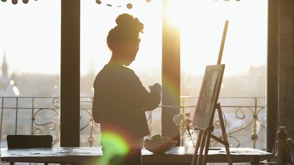 Unrecognizable Figure of Female Artist Drawing on Easel in an Art Studio with Panoramic Windows