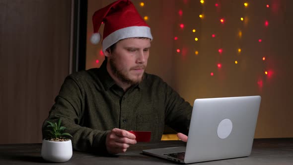 Person Holding Credit Card and Using Laptop in Home at Night