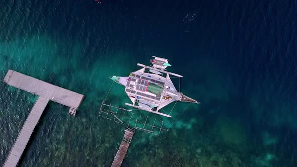 Raja Ampat islands Indonesia with Jukung boat seen from above near a pier area on a reef diving spot