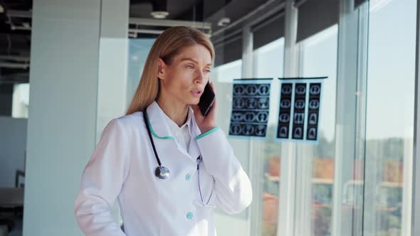 Serious Doctor Talking on Smartphone with Patient at Hospital Telemedicine