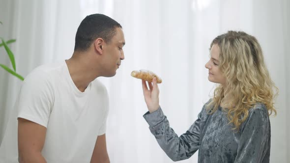 Side View of Loving Slim Beautiful Caucasian Woman Feeding African American Handsome Man with