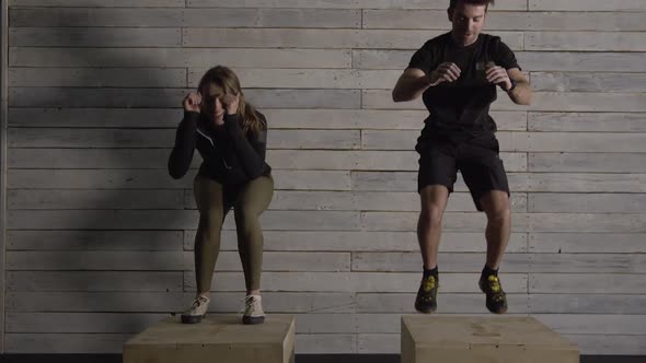 Couple working out together as they jump on boxes