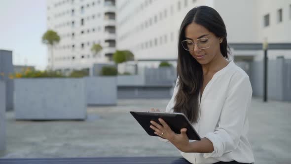 Concentrated Latin Businesswoman Using Digital Tablet in City