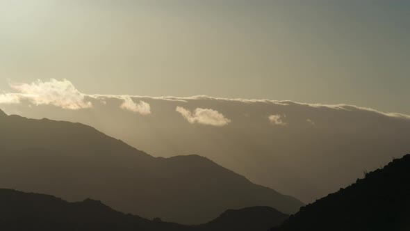 Time lapse of Sun Setting Behind Clouds and Mountains