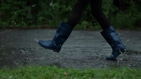 Closeup  Girl in Blue Rubber Boots Running Through the Puddles