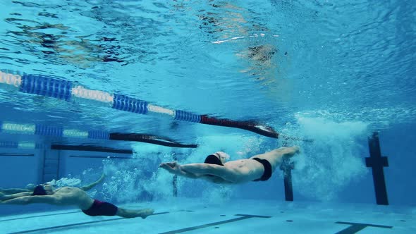 Male Athletes Swim on Their Backs Underwater