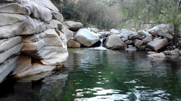 Flying Over Clear River with Rocks in the Mountain.