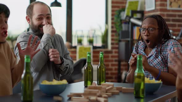 Male Player Losing at Society Game with Wooden Tower on Table