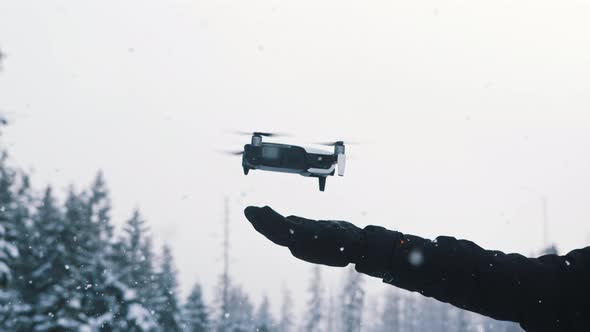 Drone Landing on the Hand of the Owner on Snowy Winter Day