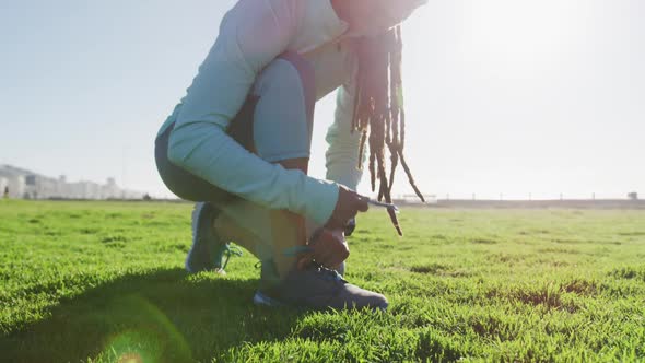 African american woman in sportswear tying her shoelaces in park