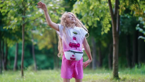 Cute little girl in the park. Carefree little girl dancing on grass and having fun in park