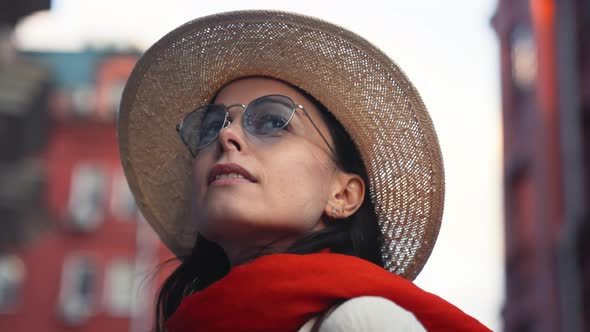 Beautiful young girl in a hat and sunglasses on a walk in the city