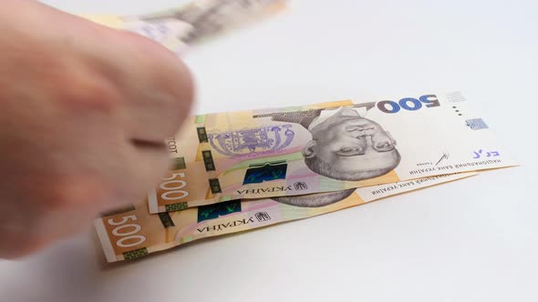 Recalculation of money. Hands count Ukrainian hryvnia bills on white background. Slow motion.