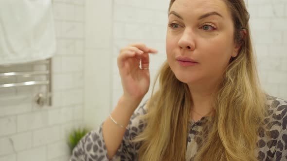 Young Woman Preens and Looks at Herself in the Mirror in the Bathroom