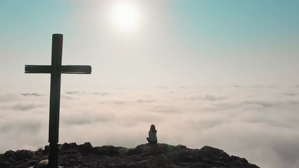 Fast Motion Zoom Out View Of Female Person Sitting On Hill Above Clouds