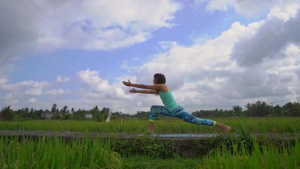 Slowmotion Steadicam Shot of a Young Woman Practicing Yoga on a Beautiful Rice Field