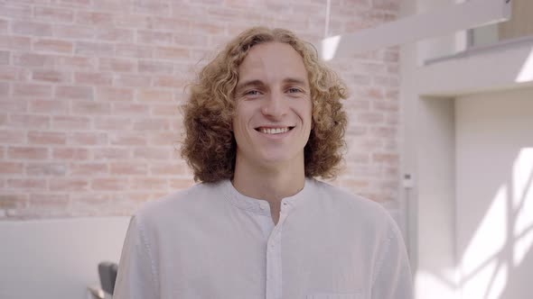 Portrait of a Smiling Young Blond Professional Man Standing in Corporate Office Looking at Camera