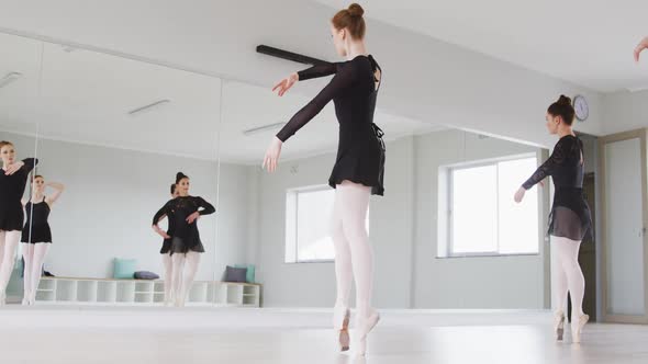 Caucasian female ballet dancers practicing a dance routine during a ballet class