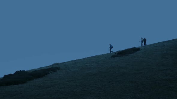 Hikers Group Of People Walking Down Hillside At Dusk