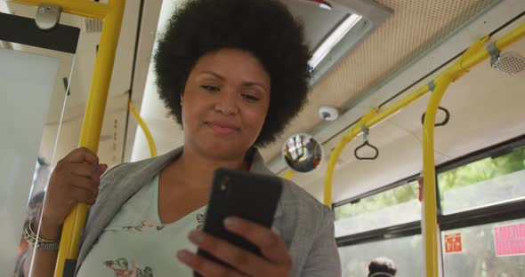 Happy plus size biracial woman using smartphone in bus