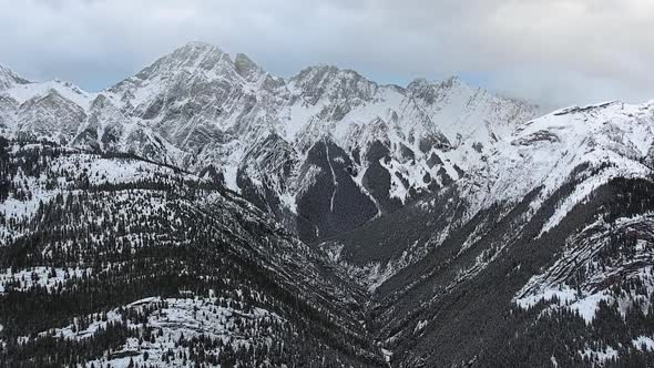 Stunning snowy mountains with wooden slopes from flight altitude in Kananaskis, Alberta, Canada