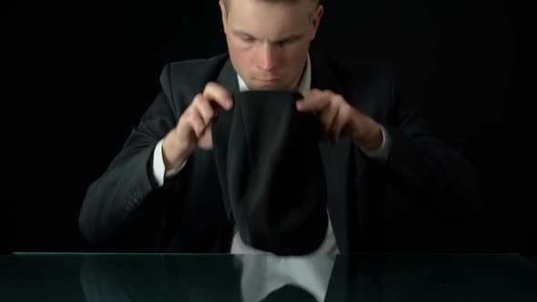 Male in Suit Putting on Balaclava, Government Corruption, Black Background