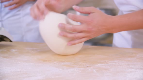 Closeup of Dough Kneaded By Baker on a Wooden Board Sprinkled with Flour