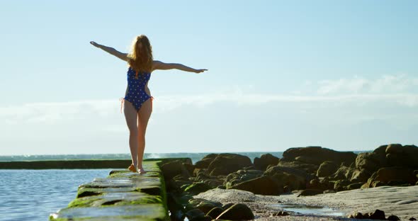 Woman walking with arms outstretched at beach 