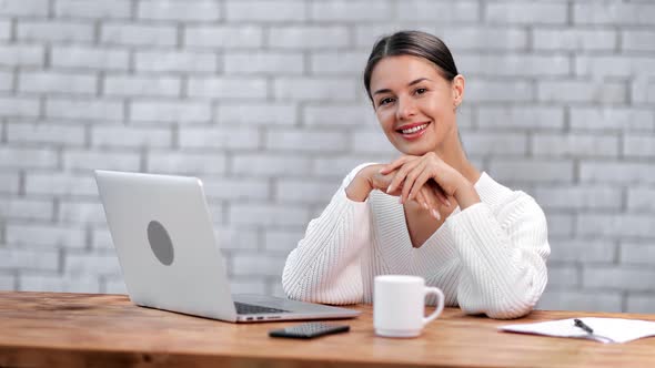 Stylish Businesswoman in White Jumper Posing at Modern Workplace