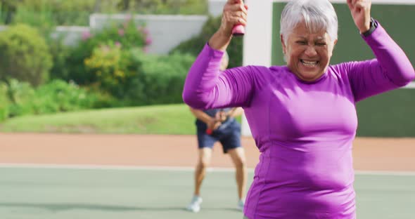 Video of happy biracial senior woman jumping with joy during tennis training