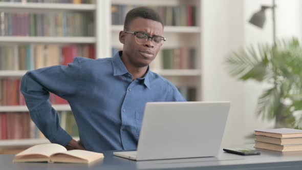 Young African Man Having Back Pain While Using Laptop in Office