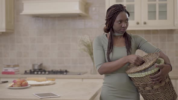 African American Woman Tired Pretty Young Woman with Dirty Laundry Basket Standing on the Kitchen