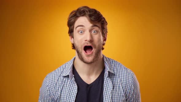 Young Casual Man Surprised and Excited of Something Yellow Background