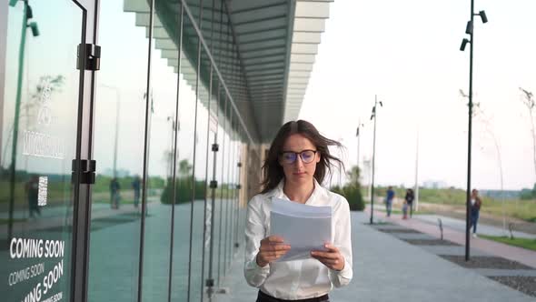 The Girl with the Papers Walks Near the Business Center of the City