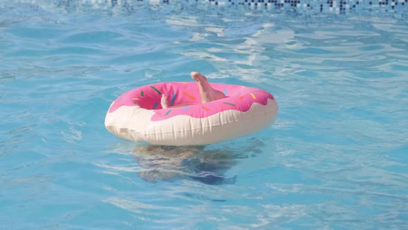 Girl in Swimming Pool Child Having Fun Sitting on Pink Donut Swimming Ring Playing Under Water