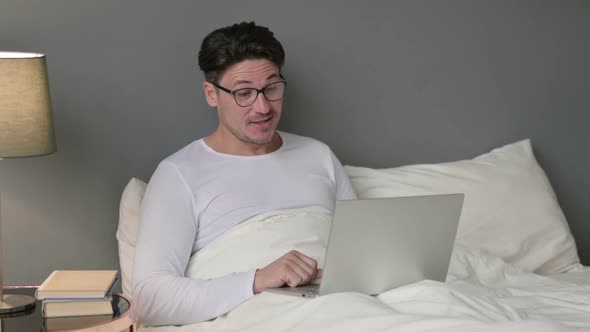 Video Call on Laptop By Middle Aged Man in Bed