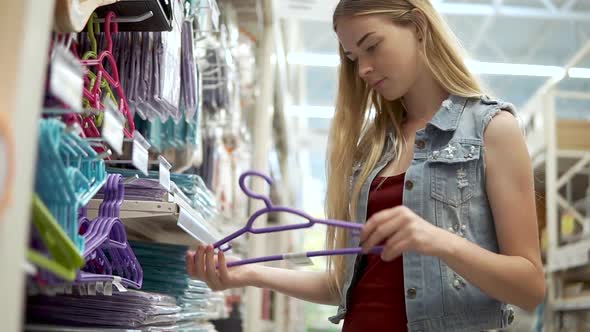 Female Shopper is Choosing Hangers for Clothes in a Shop Closeup